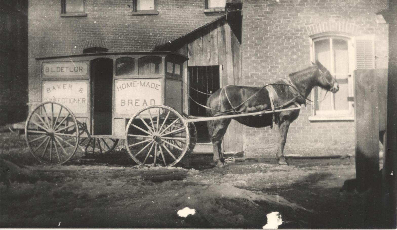 Photograph of horse and cart outside a house. The cart bears the words "B. L. Detlor, Baker & Confectioner, Home-Made Bread". Bismark Leroy Detlor owned a bake shop in St. George Street, Deseronto, Ontario. Credit: Deseronto Archives.